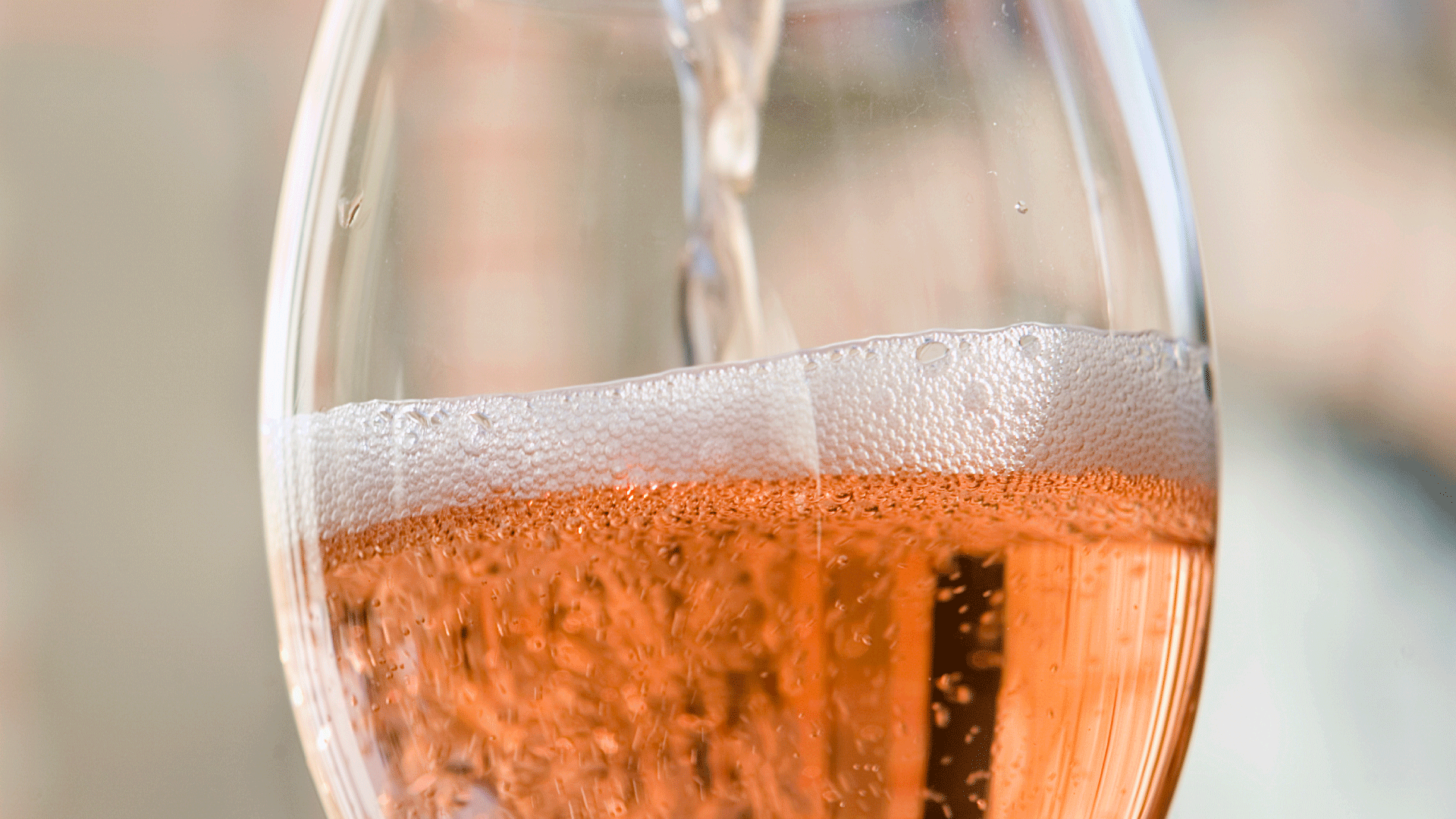 taça de espumante rosé sendo servida