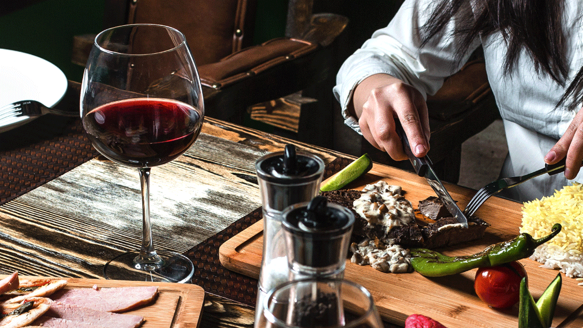 mulher comendo com uma taça de vinho tinto